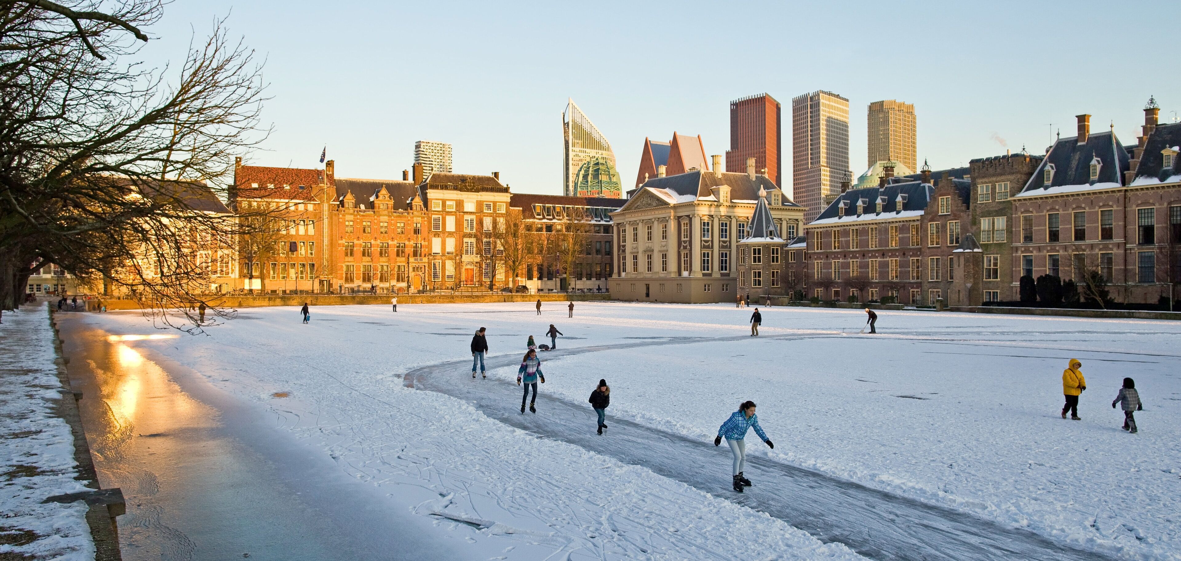 An outdoor ice skating rink surrounded by historic buildings.