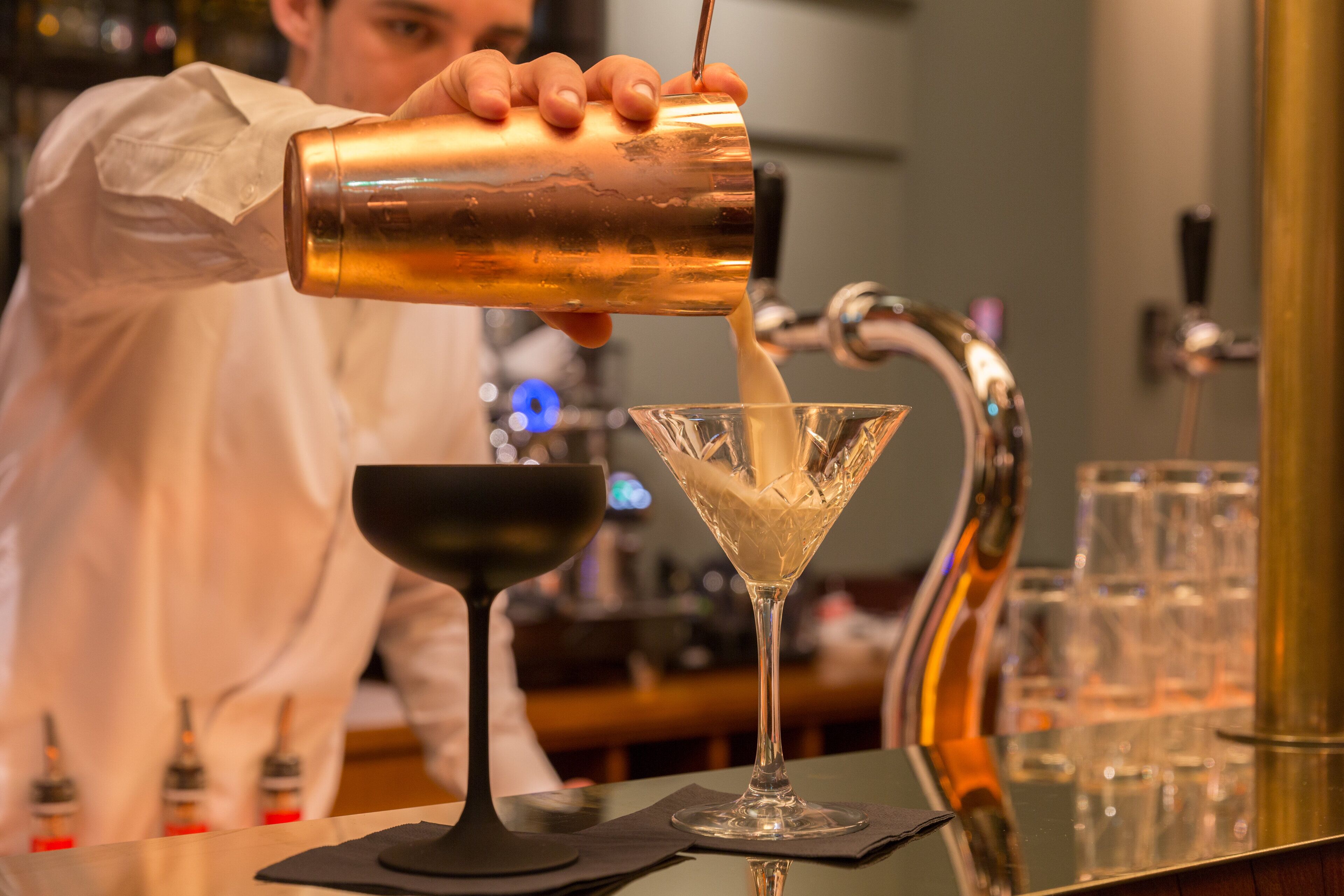 Un barman verse une boisson dans un verre à martini.