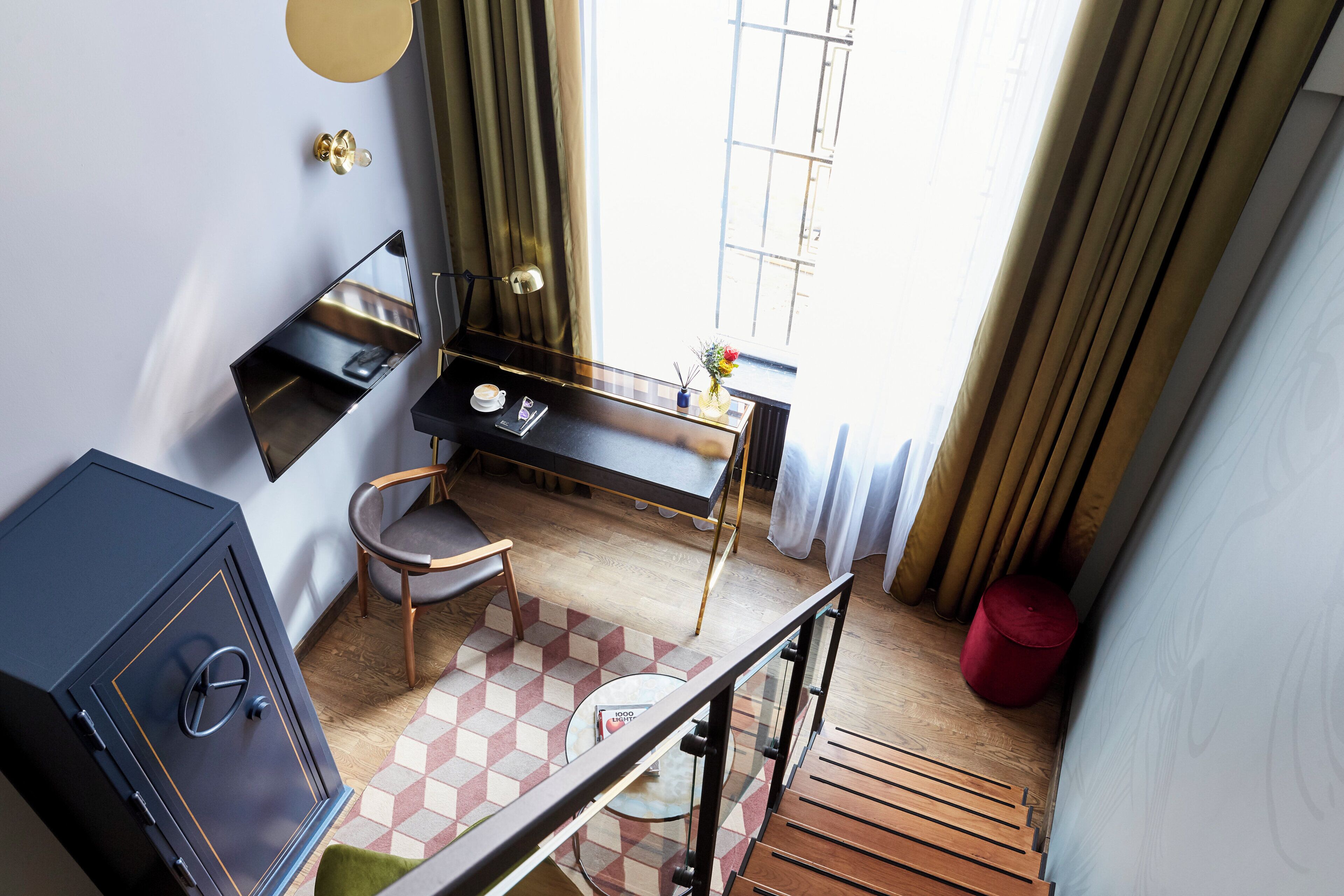 Een kleine hotelkamer met een bureau, stoel en een klein kluisje.