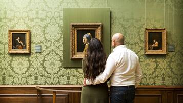 Een stel staat voor schilderijen in een groene wand met een patroon.