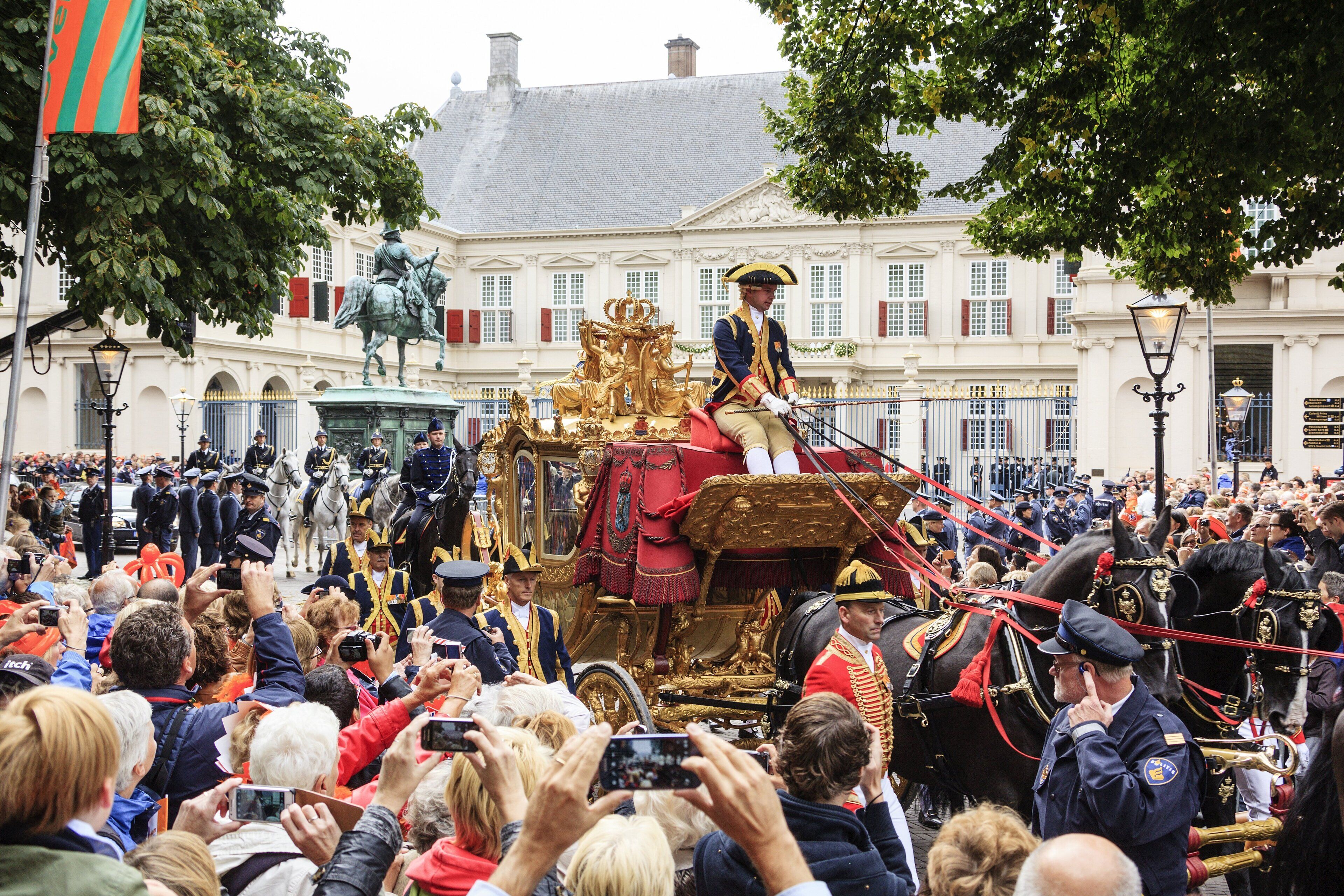 Un desfile histórico con un carruaje dorado y participantes uniformados.