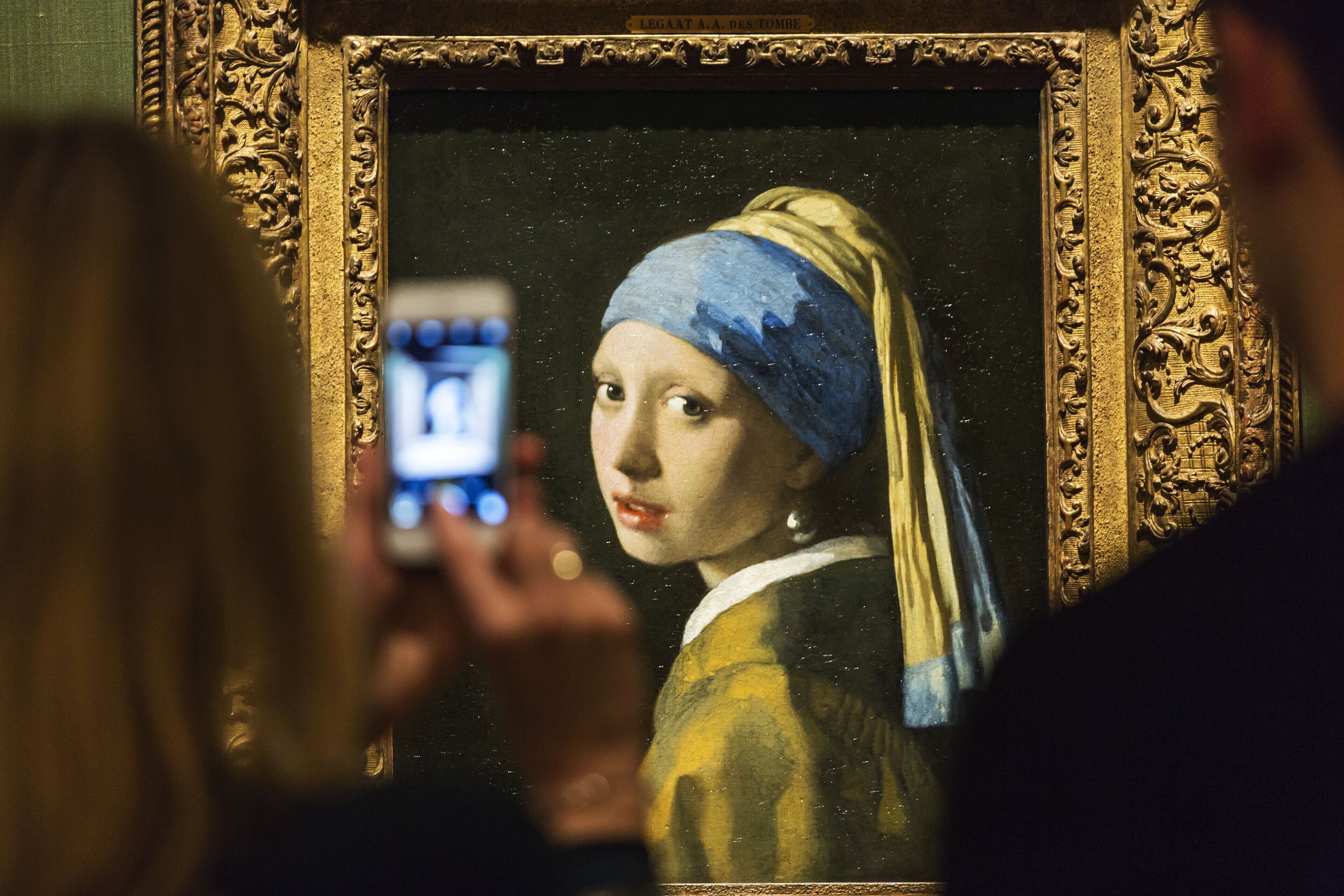 Eine Person fotografiert ein Gemälde mit einem Smartphone.