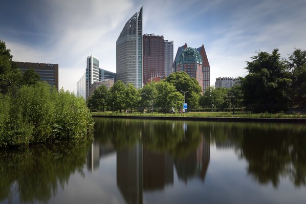Un paisaje urbano con edificios modernos, un lago tranquilo y abundante vegetación.