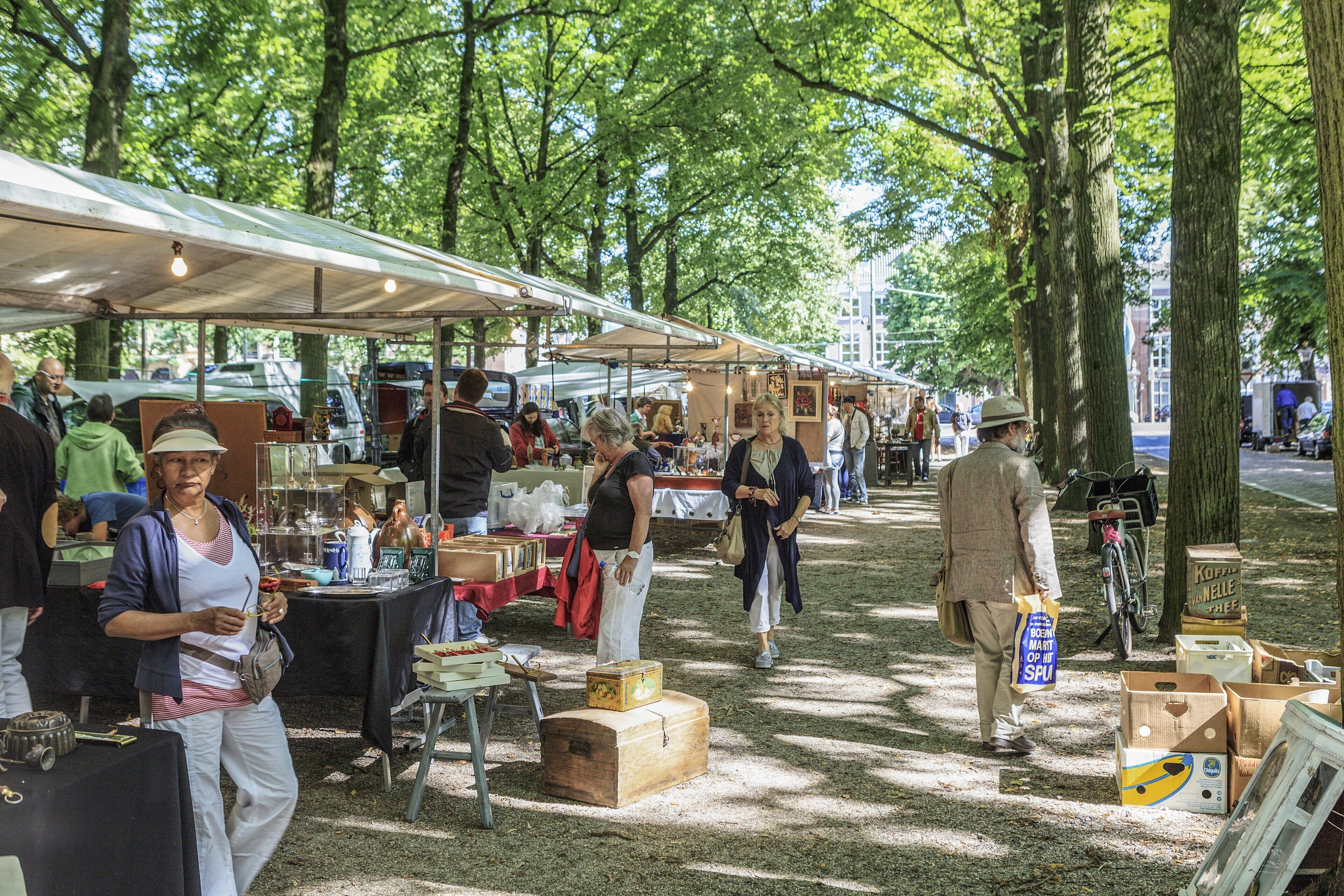 Un mercado al aire libre con varios puestos y gente mirando.