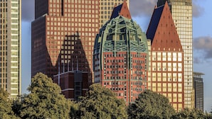 Un ensemble d’immeubles de grande hauteur, présentant un mélange de styles architecturaux, dont un bâtiment doté d’un dôme vert remarquable et un autre avec un toit rouge.