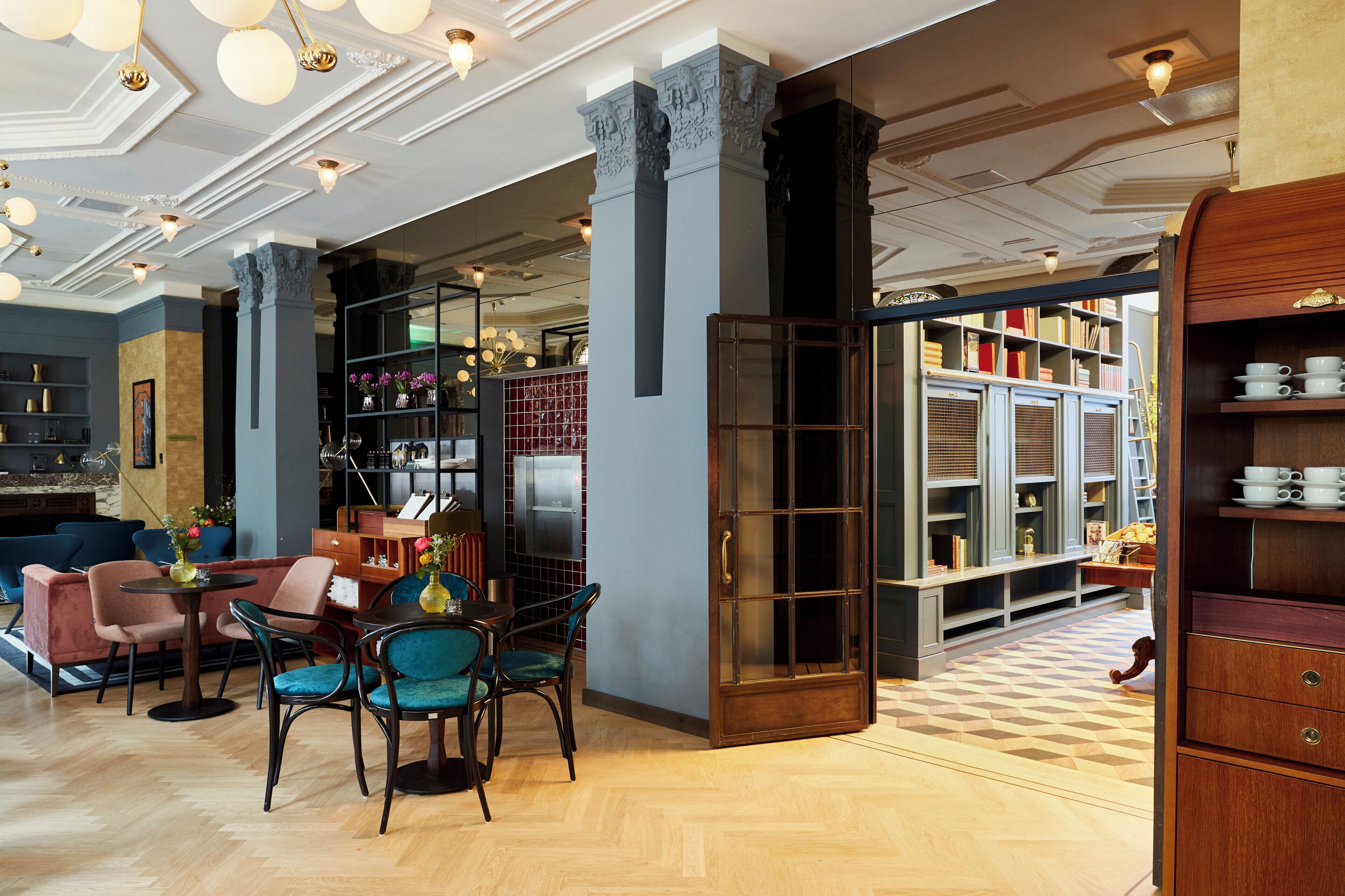 Eine Hotelhalle mit Sitzgelegenheiten, einer Bücherwand und einer Kaffeestation.