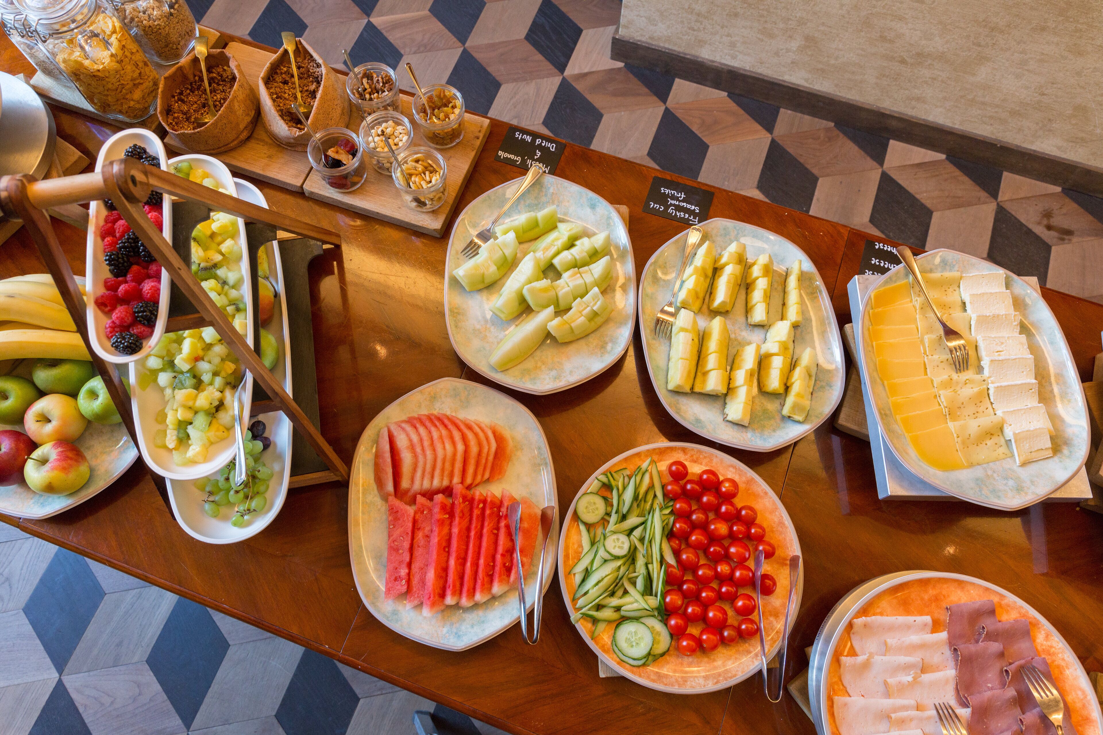 A buffet table with various food items including fruits, vegetables, and cheese.