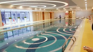 A swimming pool with a modern design, surrounded by a lounge area with seating and a staircase leading to an upper level. - Jinling Shihu Garden Hotel Suzhou (Suzhou)