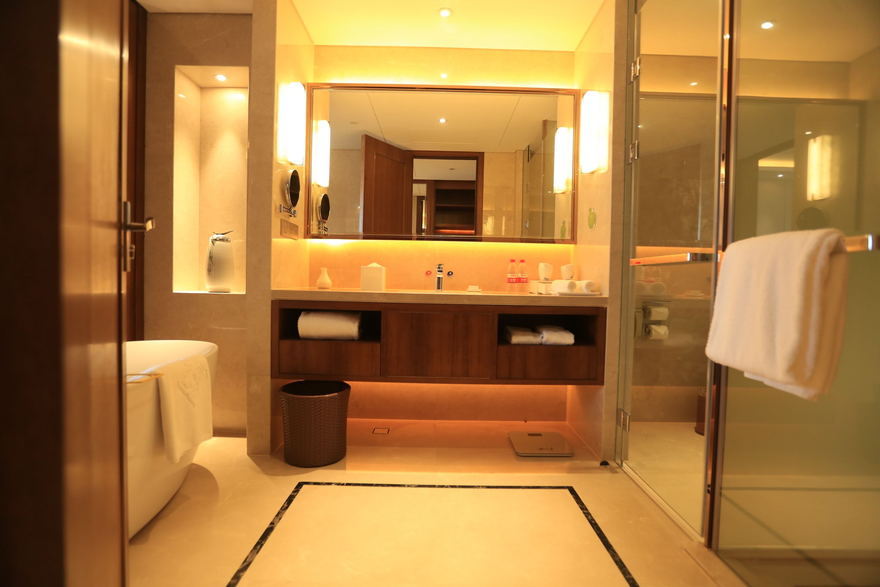 A modern bathroom with a glass shower enclosure, a large mirror, and a vanity with a towel rack.