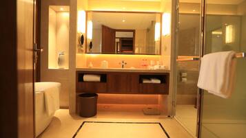 A modern bathroom with a glass shower enclosure, a large mirror, and a vanity with a towel rack.