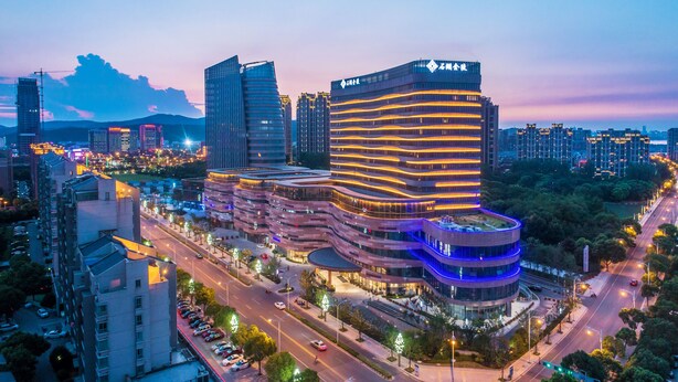 A modern hotel with a curved facade, multiple floors, and a prominent entrance. - Jinling Shihu Garden Hotel Suzhou (Suzhou)