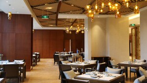 A spacious dining area with multiple tables and chairs, wooden paneling on the walls, and hanging pendant lights. - Jinling Shihu Garden Hotel Suzhou (Suzhou)