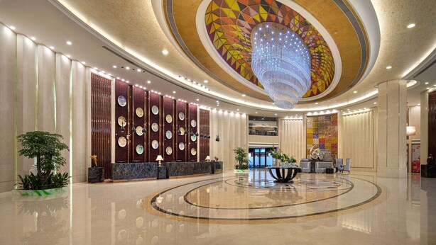 A spacious lobby with a central circular seating area, a large chandelier, and a decorative ceiling. - Wyndham Garden Foshan Nanhai (Foshan)