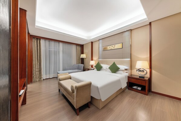 A hotel room with a large bed, a sofa, a small table, and a nightstand. - Wyndham Garden Foshan Nanhai (Foshan)