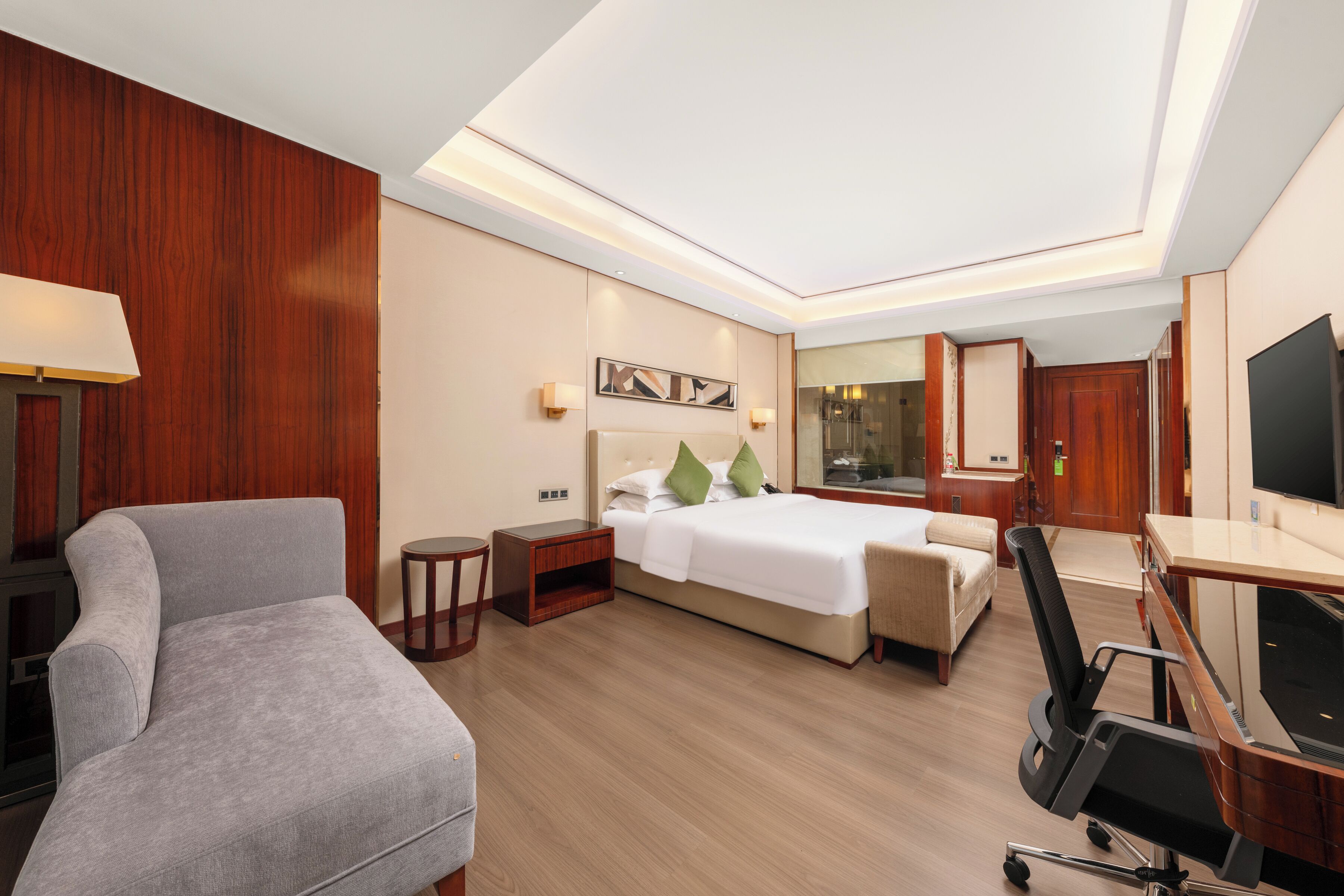 Une chambre d’hôtel avec un lit, un bureau, une chaise, une lampe et un miroir.