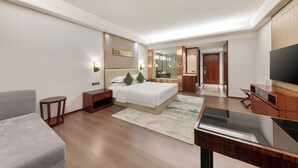 A modern hotel room with a bed, a TV, a desk, and a seating area. - Wyndham Garden Foshan Nanhai (Foshan)
