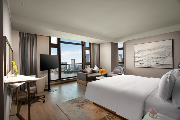 Habitación de hotel moderna con una cama grande, un escritorio, una silla y un sofá. Amplia ventana con vistas a la ciudad.