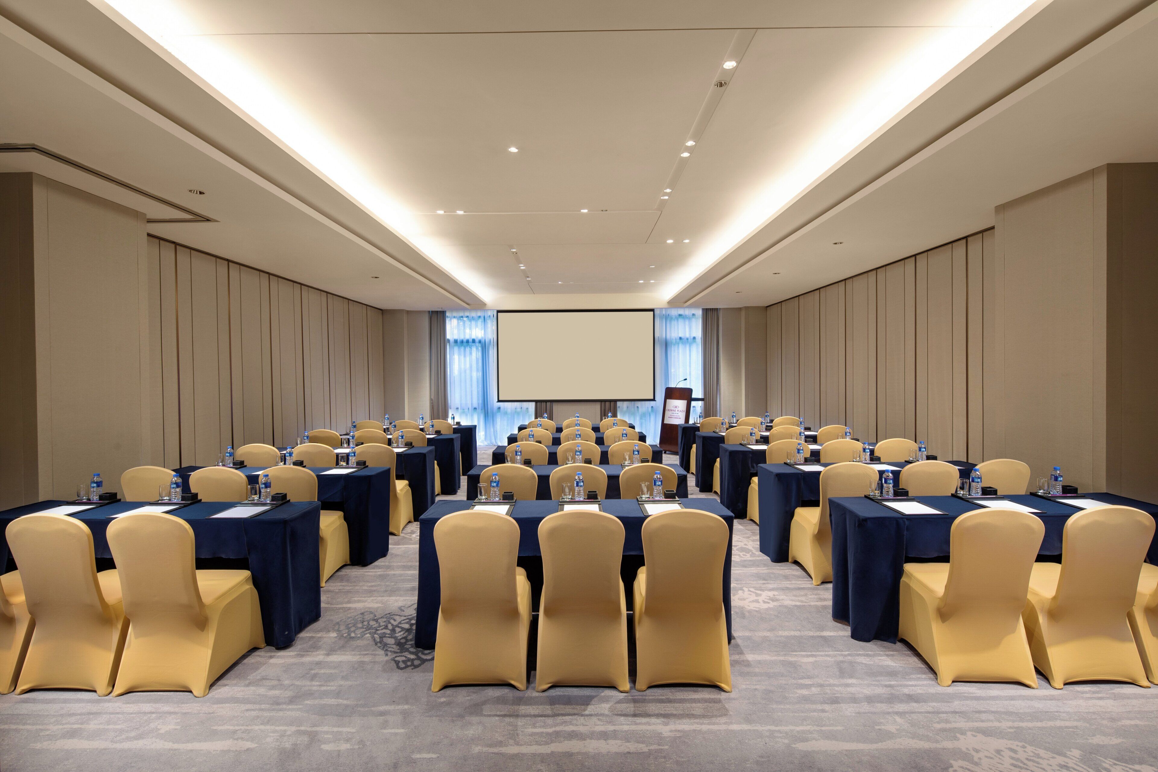 A conference room with rows of tables and chairs, equipped with water bottles and nameplates.