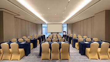 A conference room with rows of tables and chairs, equipped with water bottles and nameplates.
