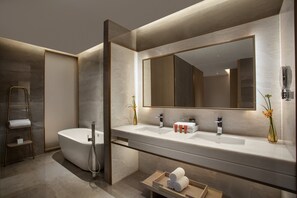 Un baño moderno con una bañera independiente, un espejo grande y un mueble de tocador con lavabo.