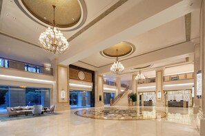 Un hall d’entrée spacieux, agrémenté d’un magnifique lustre, d’un comptoir de réception et d’un escalier menant aux étages supérieurs.