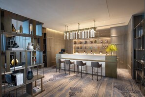 Un espace bar moderne doté d’un comptoir en marbre, de tabourets de bar et d’une variété de bouteilles d’alcool.