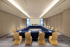 A conference room with a long table, chairs, a projector screen, and a carpeted floor. - Crowne Plaza Fuzhou South by IHG (Fuzhou)
