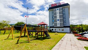 An ibis hotel with a playground, a parking area, and a garden with flowers. - ibis Igrejinha (Igrejinha)