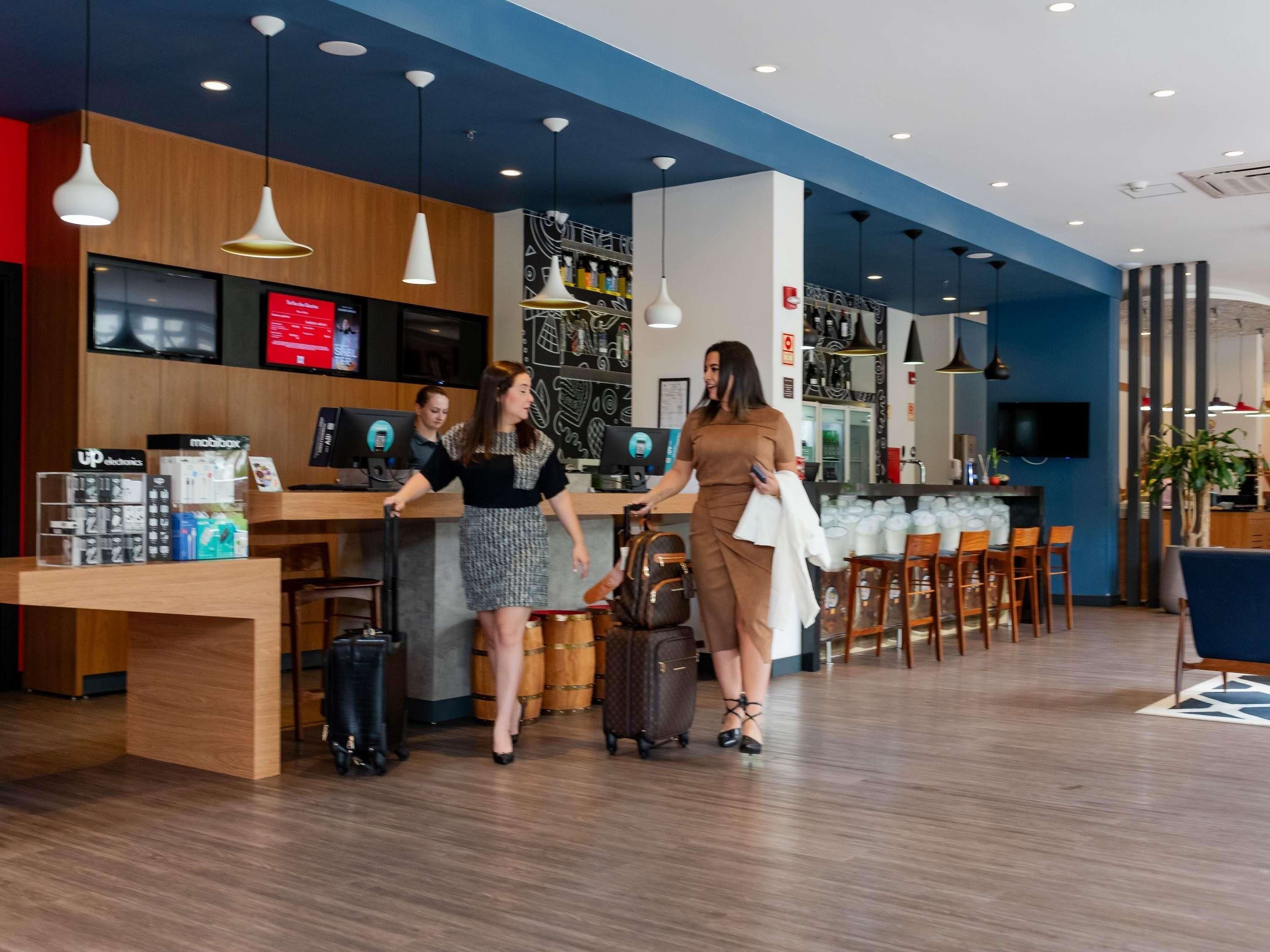 Un moderno vestíbulo de hotel con un mostrador de recepción, una zona de estar y un bar.