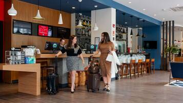 Un moderno vestíbulo de hotel con un mostrador de recepción, una zona de estar y un bar.
