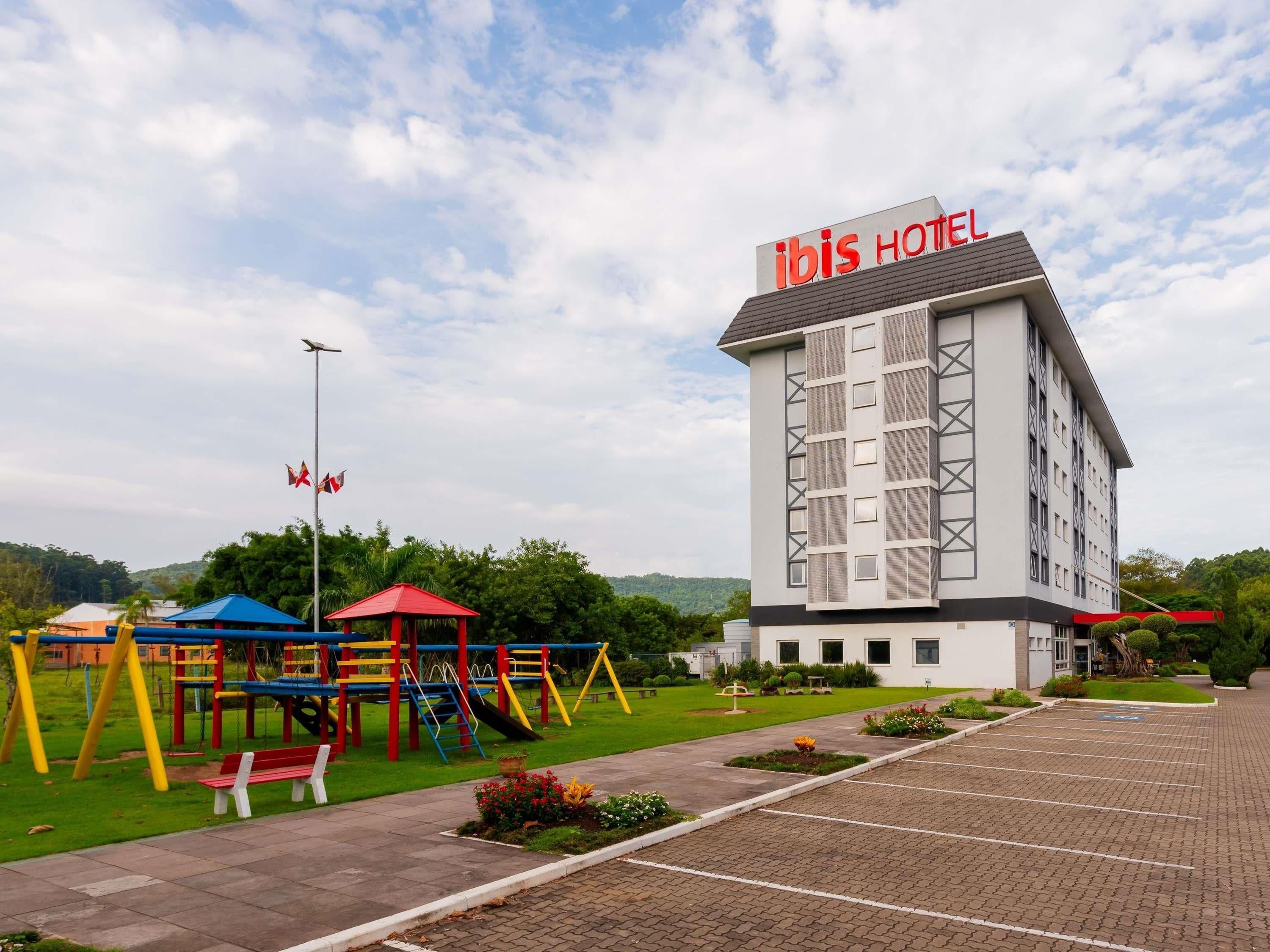 Un hotel con área de juegos, estacionamiento y cielo despejado.