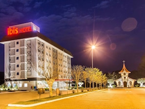 Ein Hotel mit auffälliger Beschilderung, einem Parkplatz und einem kleinen Gebäude, das einer Kirche ähnelt.
