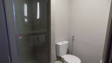 Une petite salle de bain comprenant des toilettes, une douche et un espace de douche vitré.