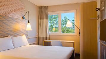 Una habitación de hotel con cama, mesitas de noche, ventana con cortinas y armario.