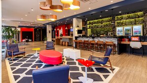 A modern lobby with seating areas, a bar, and a patterned wall. - ibis Igrejinha (Igrejinha)