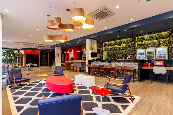 A modern lobby with seating areas, a bar, and a patterned wall. - ibis Igrejinha (Igrejinha)
