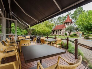 An outdoor seating area with wicker furniture and a view of a building with a red roof. - ibis Igrejinha (Igrejinha)