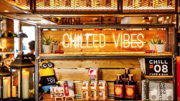 Un café con un letrero de neón que dice 'CHILLED VIBES' y un peluche de Minion. Se exhiben bolsitas de té teapigs y botellas de Midnight Oil.
