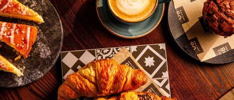 A table with a croissant, a slice of pie, a cup of coffee, and a muffin.