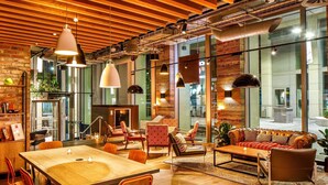 A modern interior with a wooden dining table, red chairs, and a leather sofa.