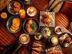 A table with various food items and drinks, including pastries, a croissant, and a glass of coffee. - ibis London Canning Town (London)