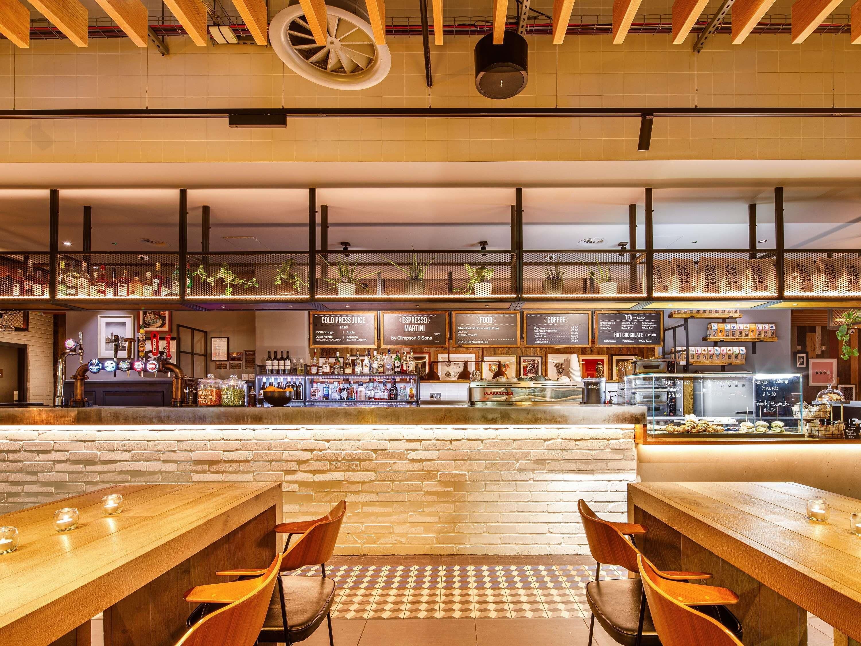 Uma área de bar com balcão, banquetas e um quadro de menu.