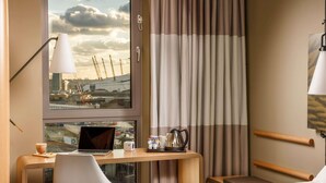 A hotel room with a desk, laptop, coffee maker, and a view of a construction site through the window.