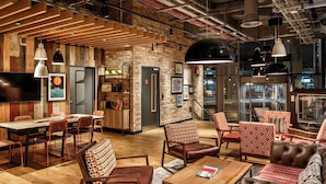 A modern interior with a wooden dining area, leather sofas, and a bar area with a brick wall.