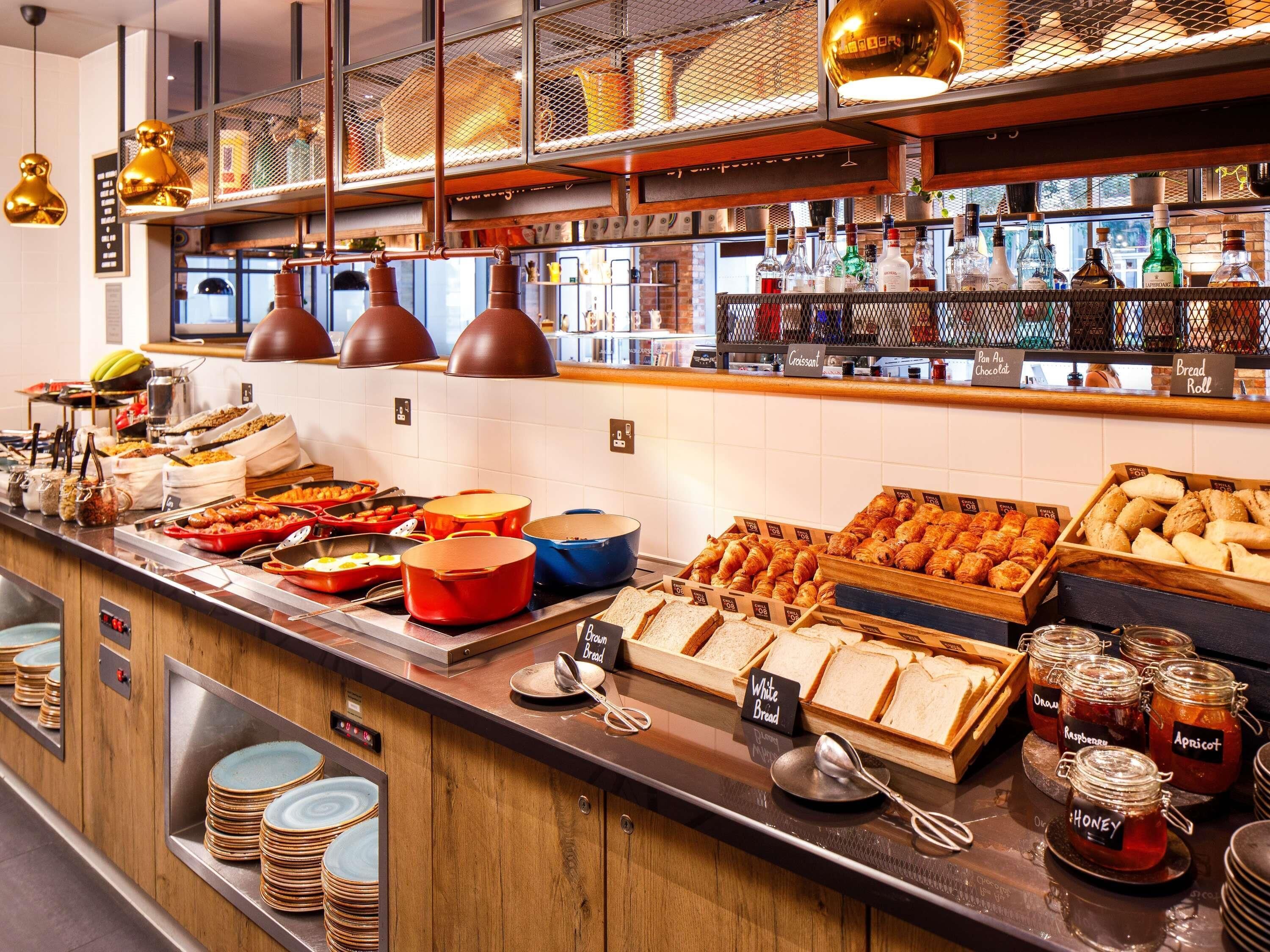A buffet area with various food items, including bread, pastries, and condiments.