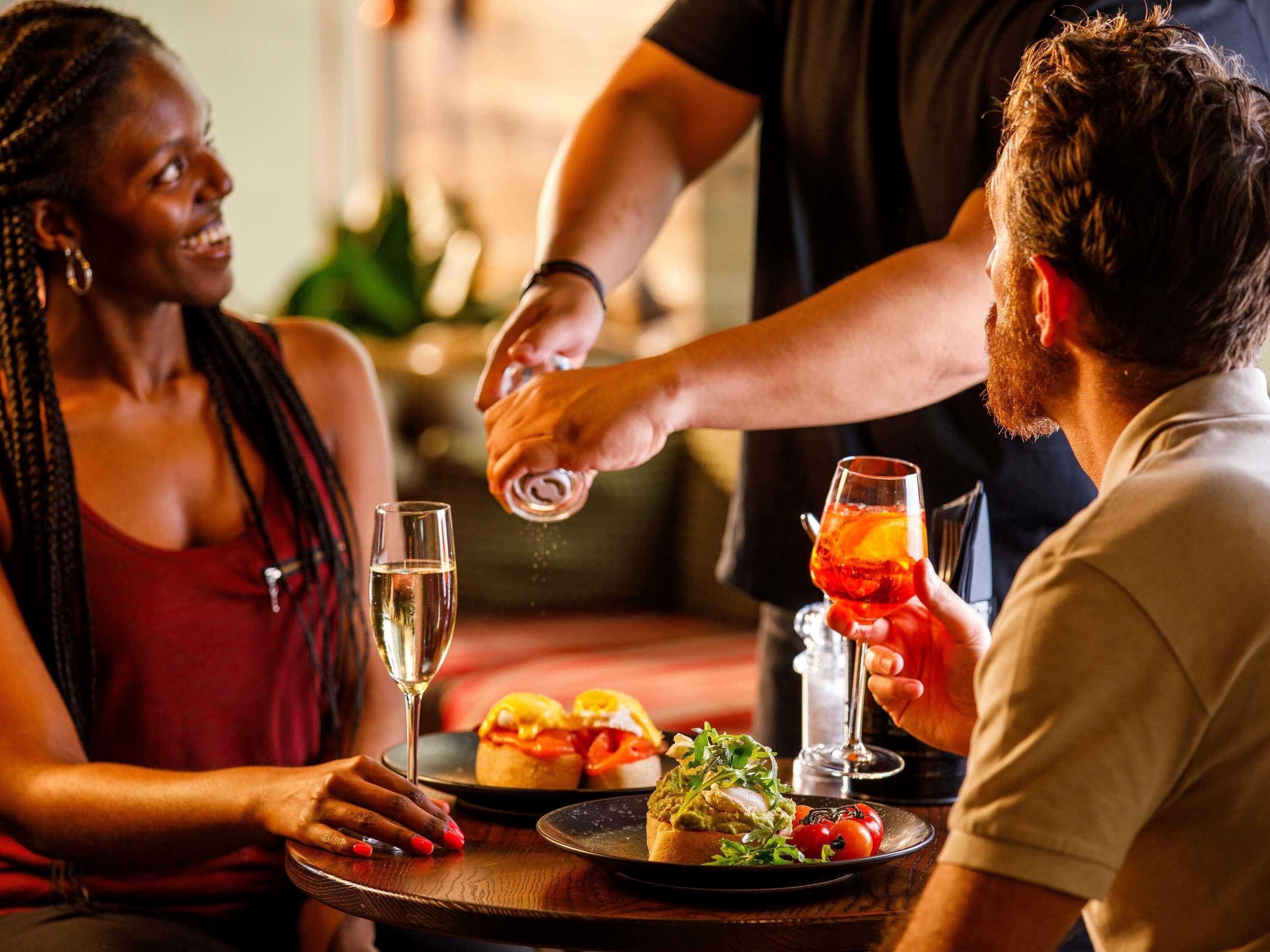 A dining table with a plate of food, a glass of white wine, and a glass of red wine.