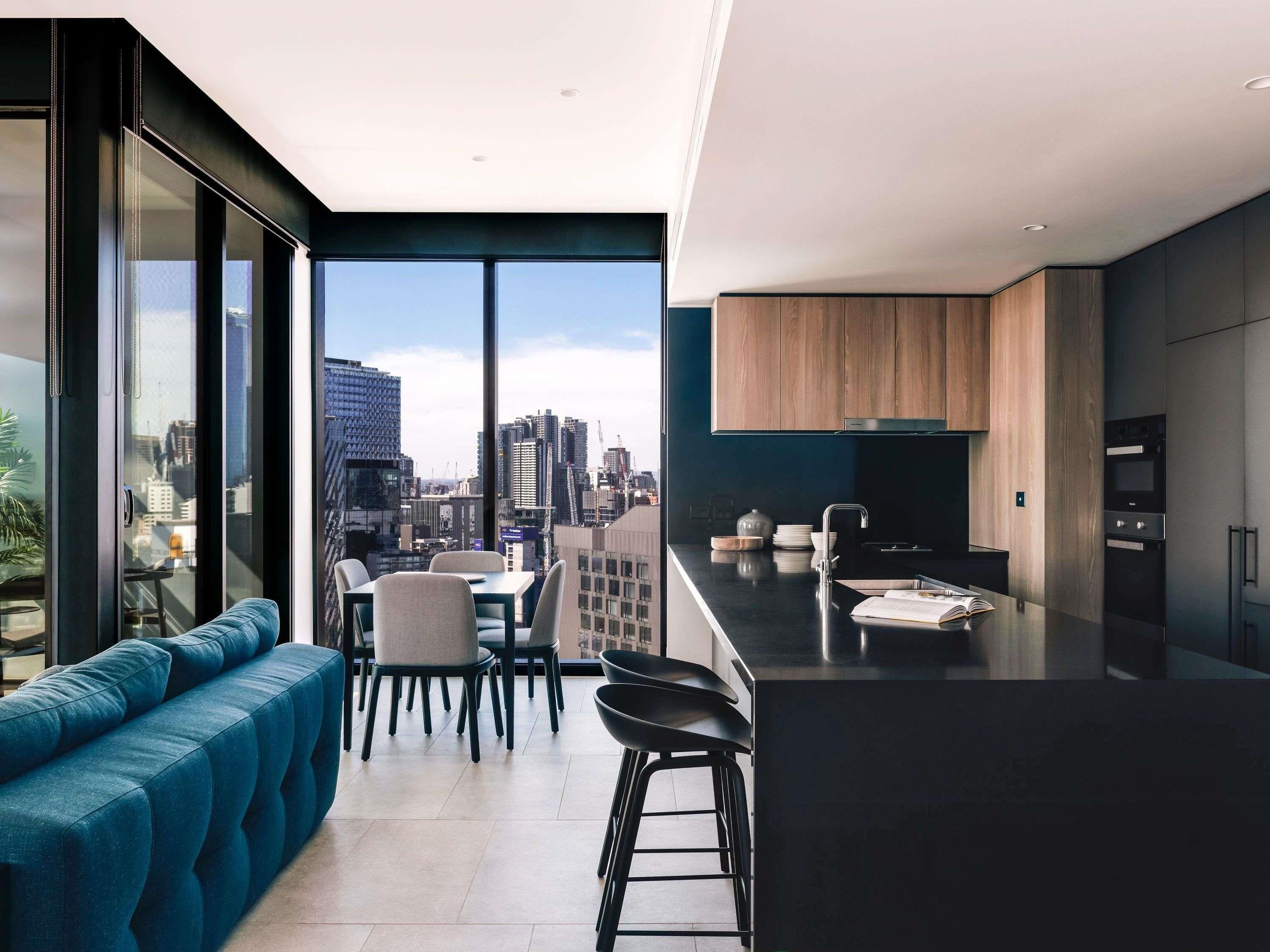 Uma cozinha moderna com vista para a cidade, uma área de jantar com sofá azul e uma janela grande.