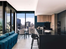 A modern kitchen with a city view, a dining area with a blue sofa, and a large window.