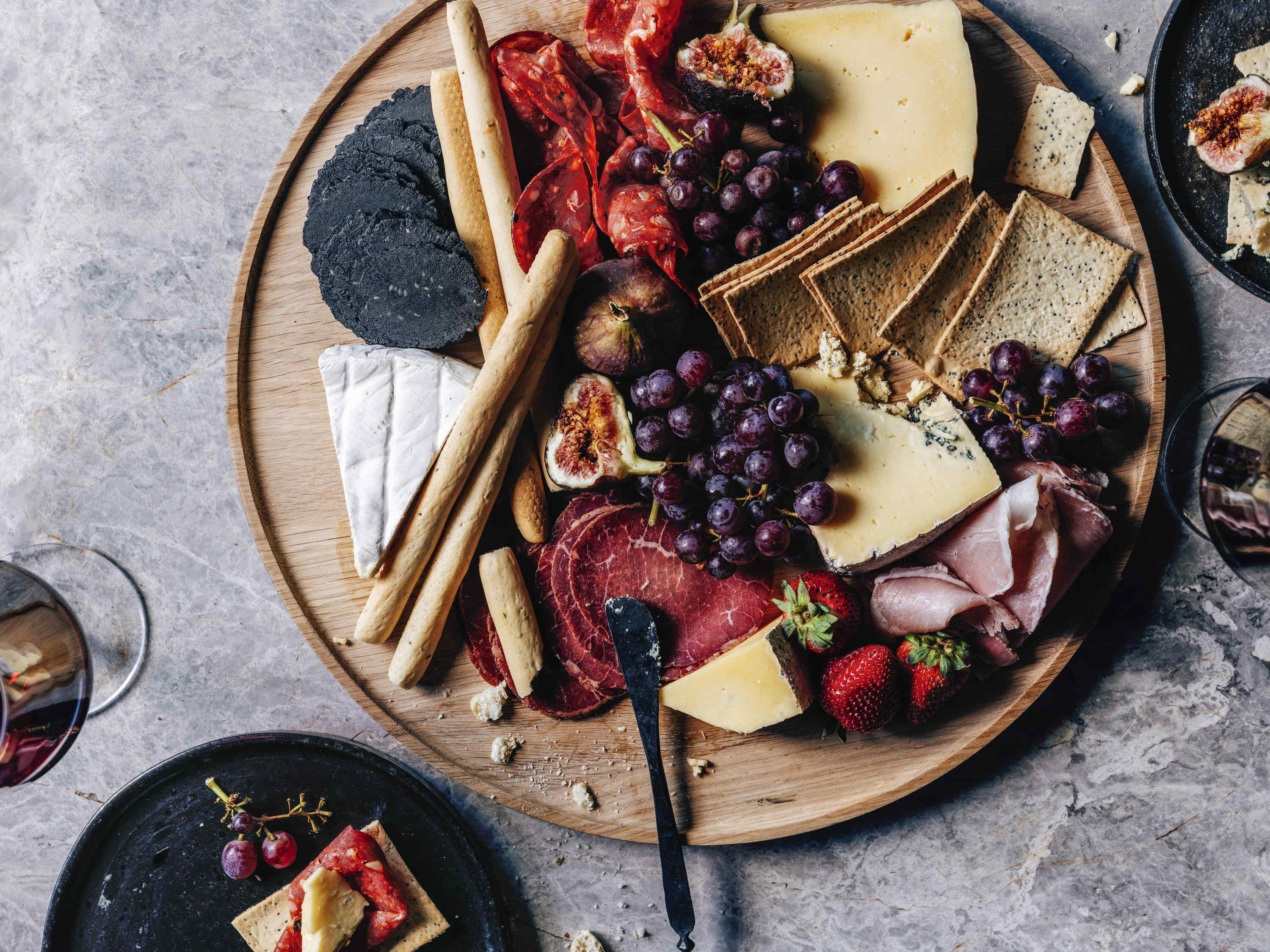 A charcuterie board with various cheeses, meats, fruits, and crackers.