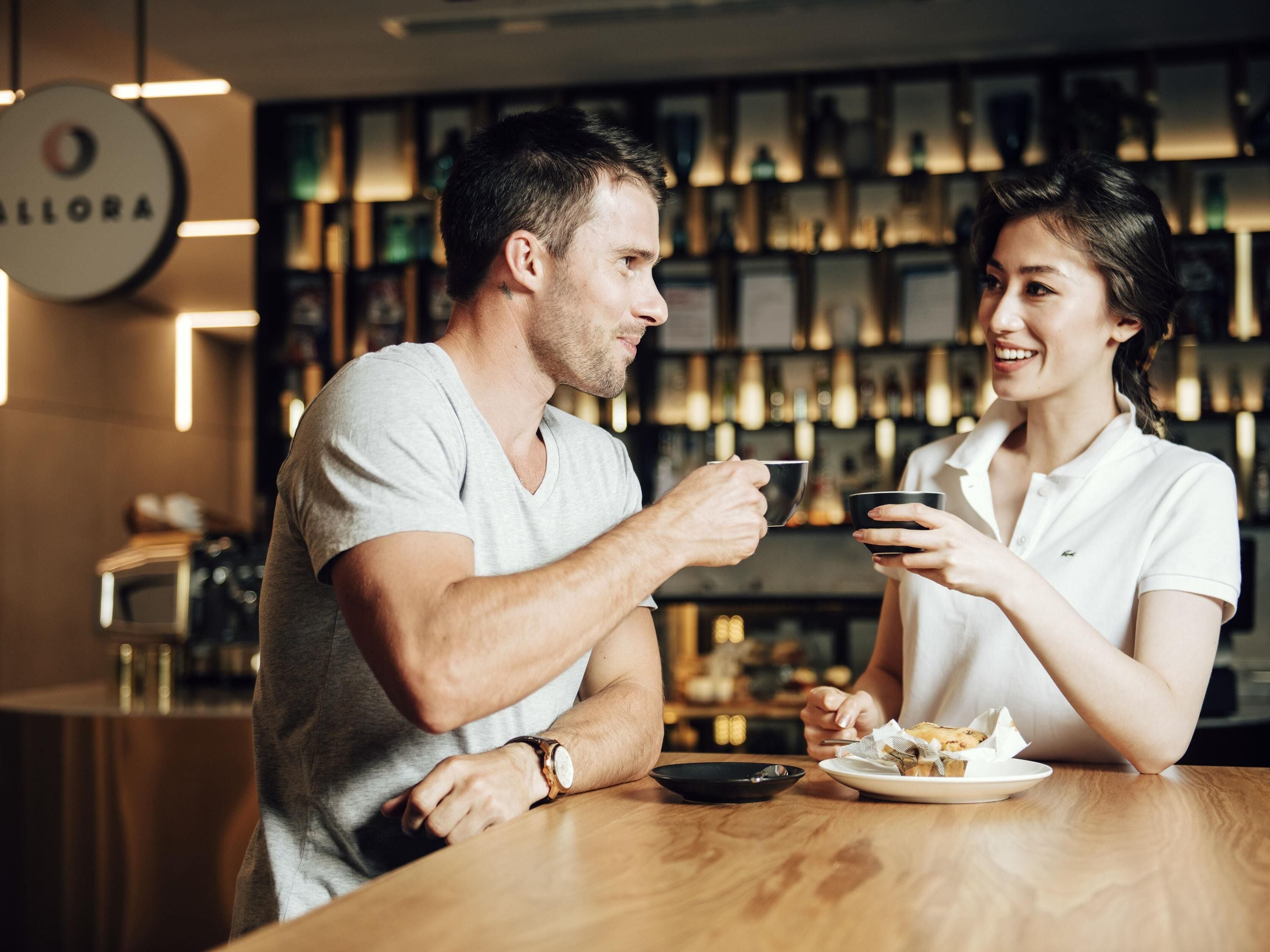 Two people sitting at a wooden table in a restaurant with a bar in the background.